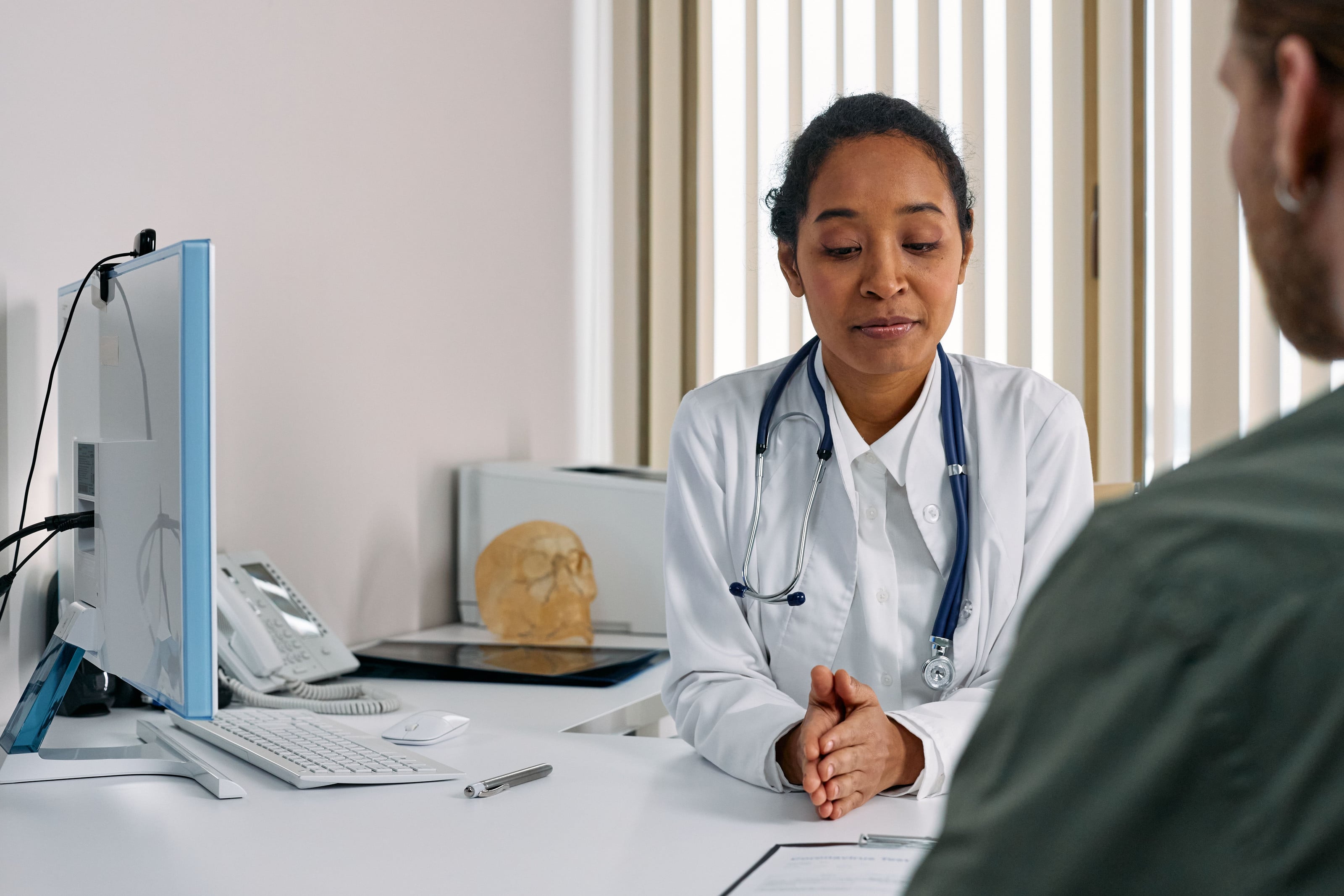 Médica escuchando a un paciente en el consultorio