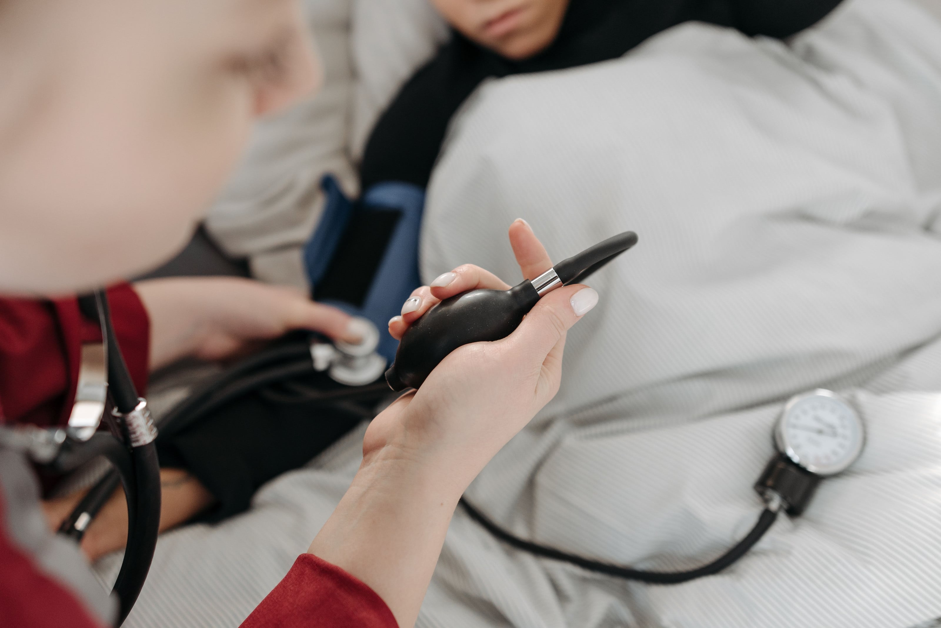 Profesional de la salud tomando la tensión arterial a una paciente en su cama