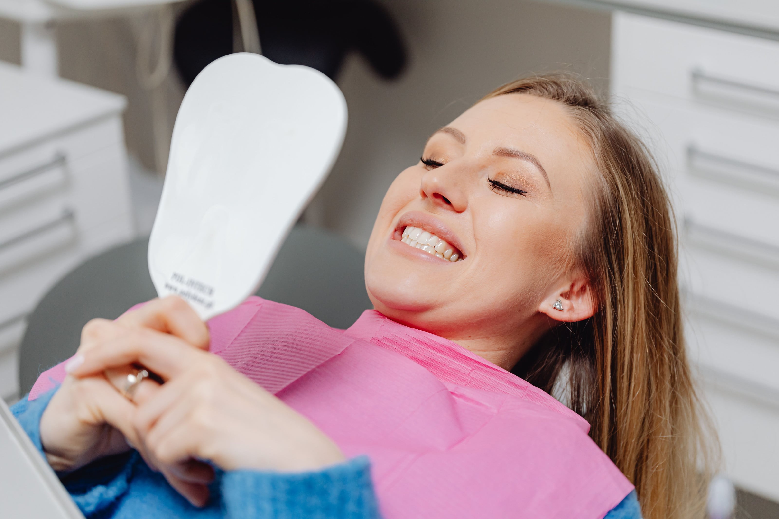 Paciente sonriendo frente a un espejo en la silla odontológica
