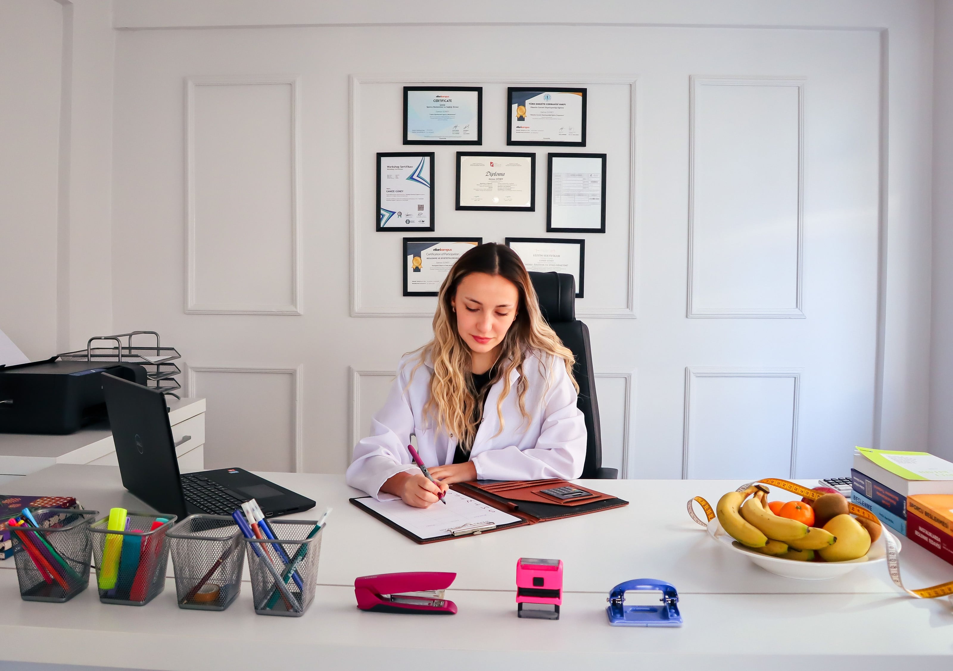 Nutricionista escribiendo en su escritorio, con fruta al lado