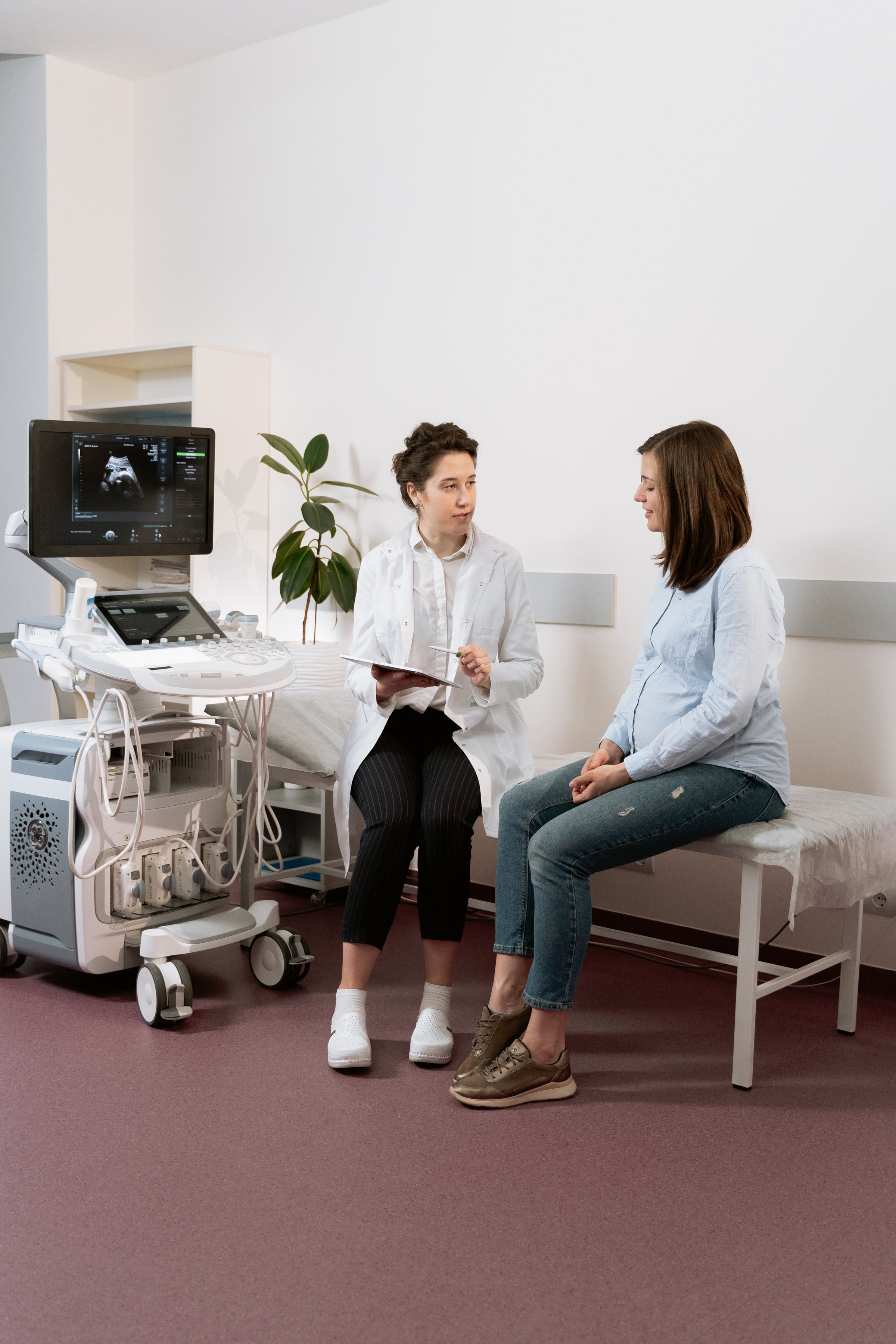 Médica y paciente conversando junto al ecógrafo en el consultorio