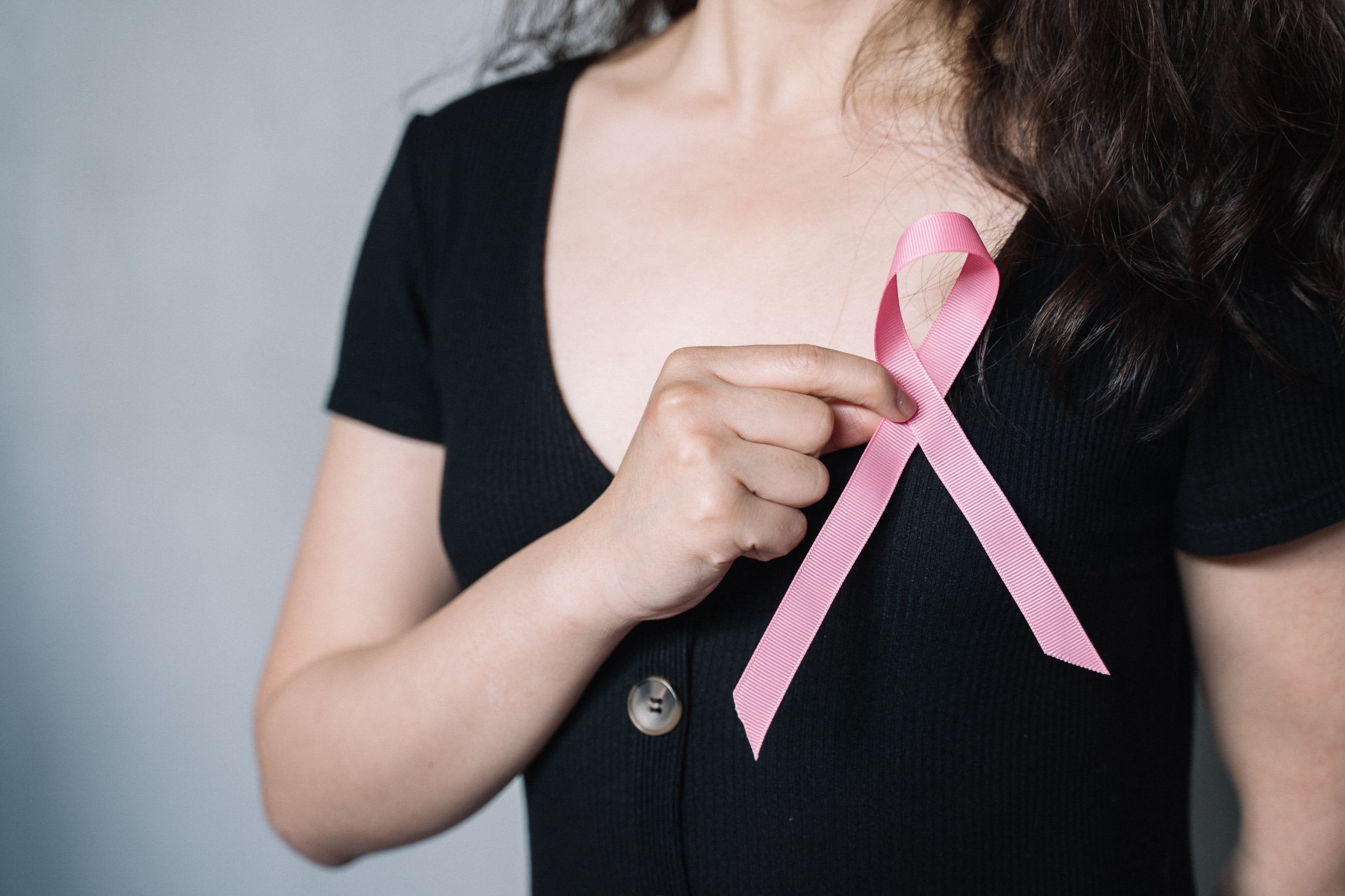 Mujer sosteniendo el lazo rosado de la lucha contra el cáncer de mama